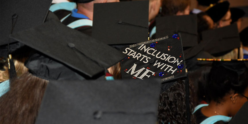 Image of student at graduation with "inclusion starts with me" on her graduation cap.